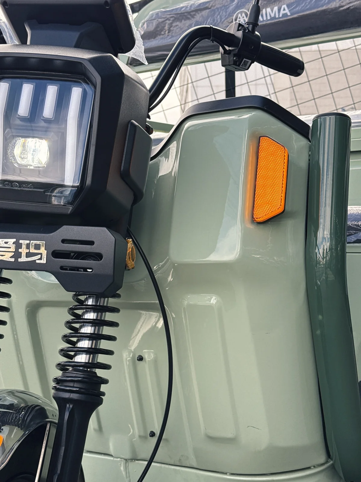 Detalhe do farol, indicador lateral e suspensão dianteira do AIMA Tank verde
